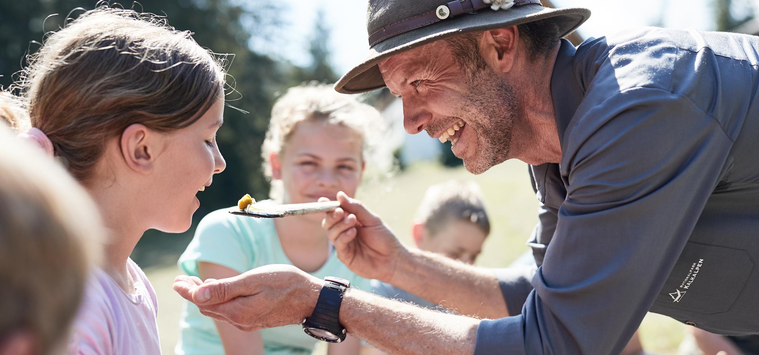National Park Ranger hands a girl food on a wooden spoon