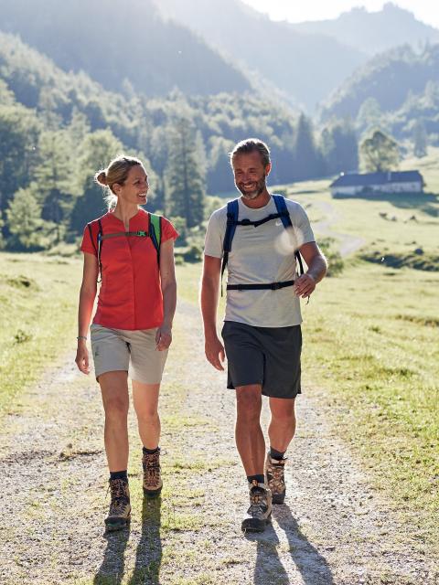 A couple walks across an alpine pasture at the foot of the Sengsengebirge.