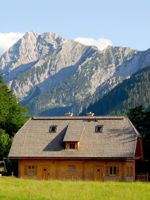 Wooden building of the Hengstpasshütte in the background a rocky mountain backdrop