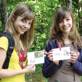 Two girls holding animal cards labeled in English