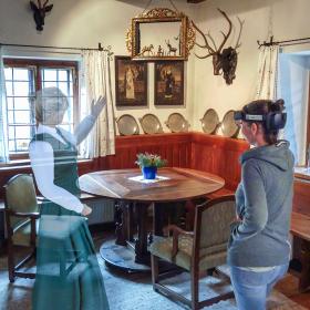 The virtual Anna von Lamberg shows a visitor a red deer trophy during an augmented reality tour in the Bodinggraben forester's lodge.