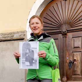 Ranger stands in front of the church portal showing the old wedding photo of Marlen Haushofer in her hand