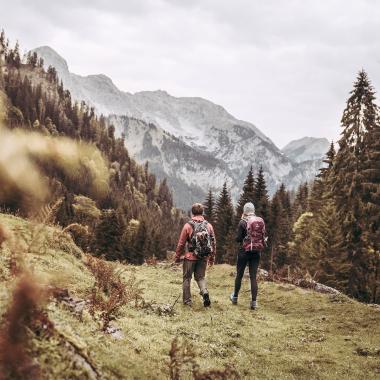 A woman and a man with a backpack hike together through an autumn landscape