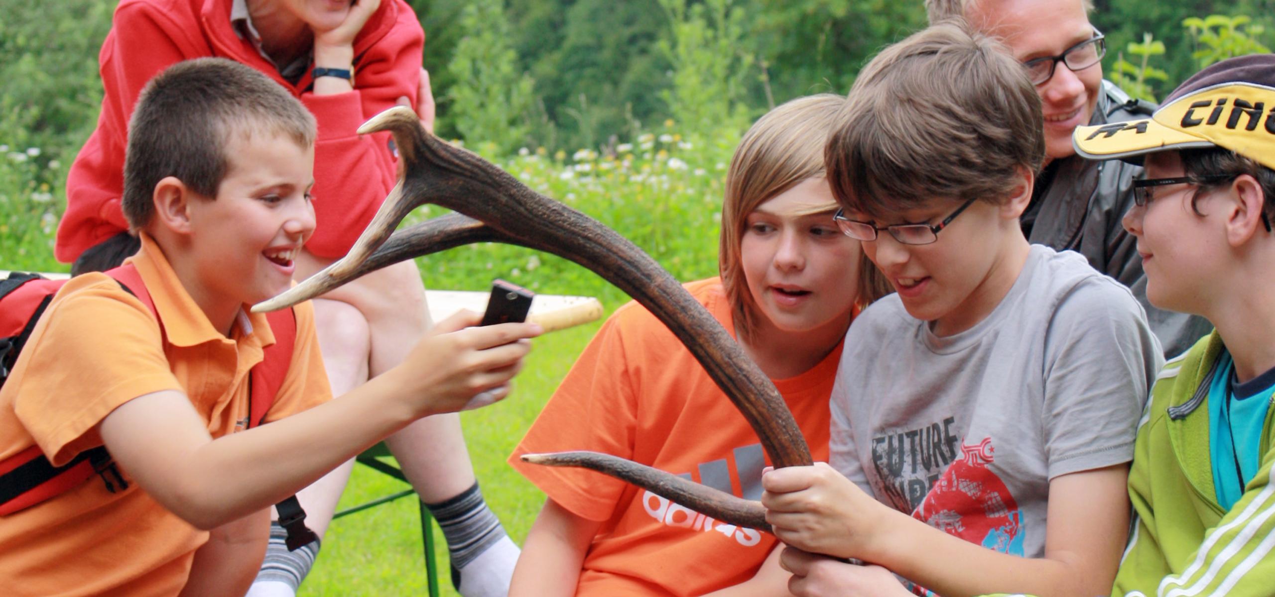Young people hold a deer antler in their hands