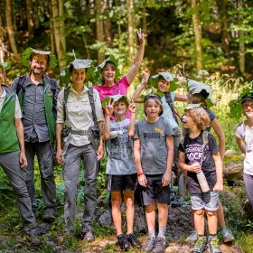 A group of children with a national park ranger using large leaves as a sun hat