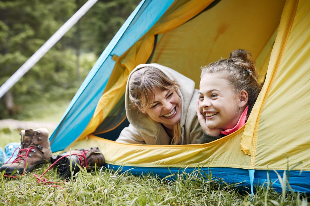 Mother and daughter look out of the tent entrance and have fun