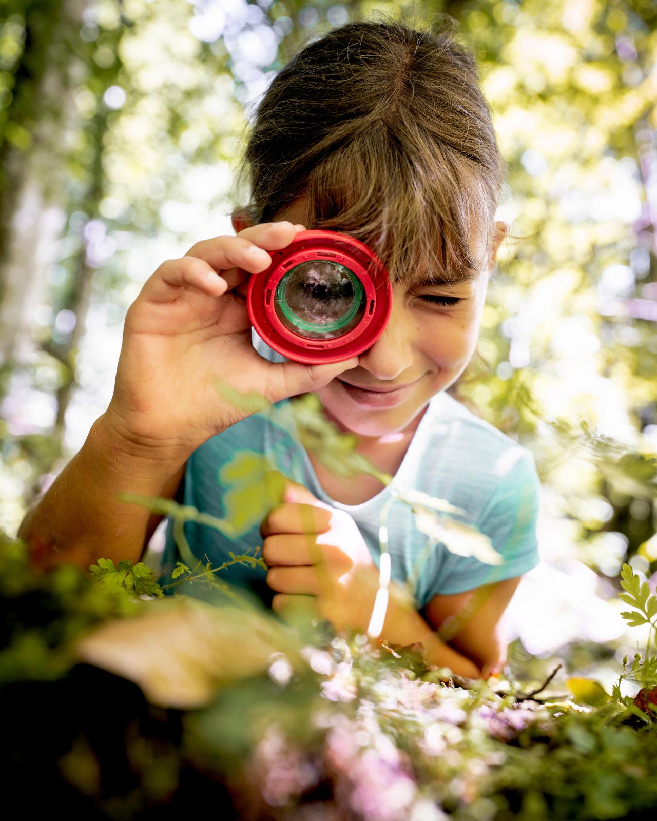 Girl looking at a beech leaf through a magnifying glass