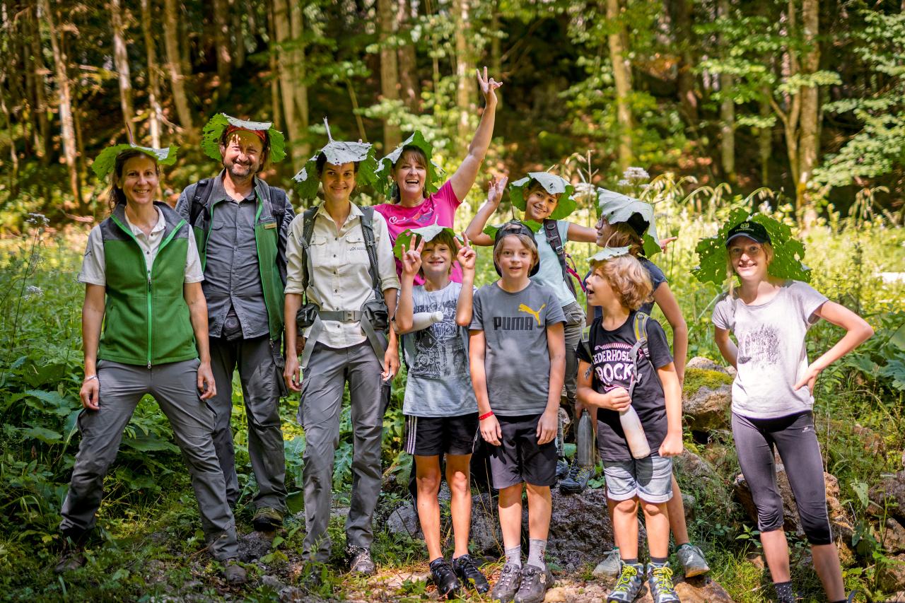 A group of children with a national park ranger using large leaves as a sun hat