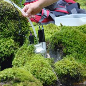 A water meter is stuck between mossy stones in the mountain stream