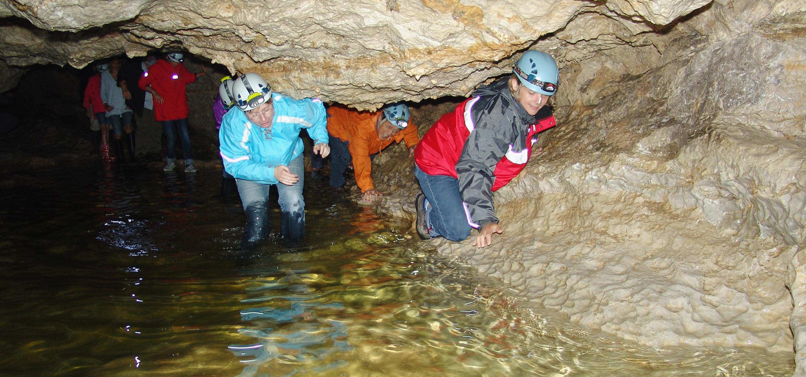 Children and adults press themselves along the cave wall