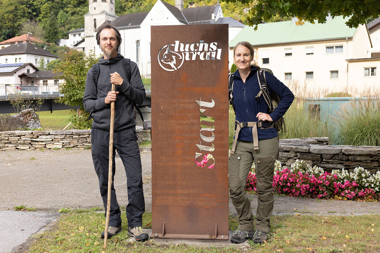 Marc Graf and Christin Sonvilla stand at an iron monument with the words Luchs Trail Start.